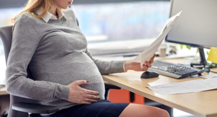 Eine schwangere Geschäftsfrau liest Dokumente im Büro